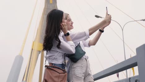 Happy-Asian-lesbian-couples-selfie-video-chat-with-friends-enjoying-traveling-in-Thailand.-Beautiful-young-women-having-fun-in-vacation-time.-LGBT-concept.