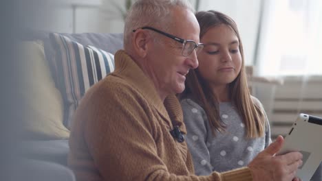 Großvater-und-Enkelin-mit-Tablet-und-Lachen