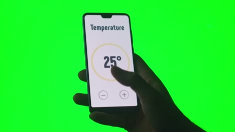 Die-Hand-steuert-die-Smart-Home-App-mit-einem-Smartphone-auf-grünem-Chromakey-Hintergrund