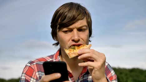 Mann-surft-Internet-mit-Telefon-essen-Pizza-in-grünen-Park