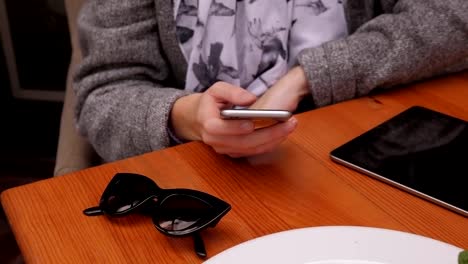 Die-Hand-einer-Frau-mit-einem-Telefon-und-einem-Tablet-in-einem-Straßencafé.-Nahaufnahme.