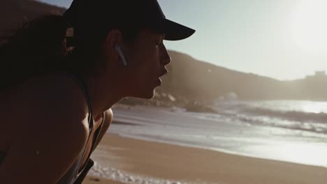 Woman-with-earbuds-resting-after-run-at-the-beach