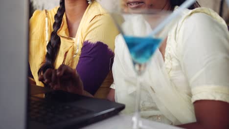 Two-women-chilling-sipping-drinks-using-technology-in-cafe