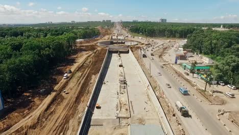 drone-is-flying-along-construction-of-roads-and-brand-new-traffic-circle,-cars-are-moving-in-detour