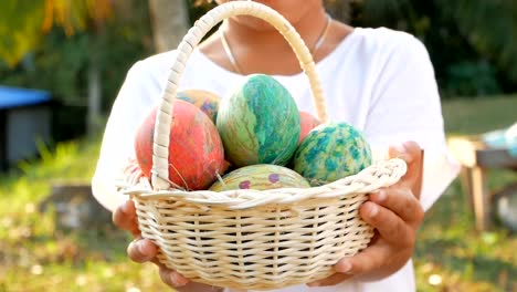 Close-up-of-children-hand-holding-a-basket-with-easter-eggs-in-sunshine-background