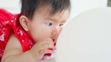 Cute-asian-little-baby-girl-having-fun-to-try-to-catch-and-play-with-balloon-in-slow-motion-shot