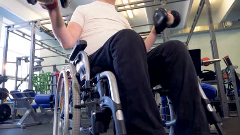 Close-up-view-of-dumbbells-in-disabled-man's-hands.