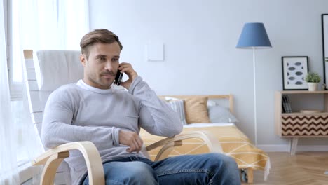 Adult-Man-Talking-on-Phone-while-Relaxing-on-Chair