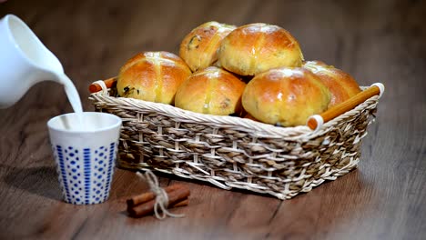 Pascua-Hot-Cross-bollos-en-una-cesta.-Vierte-la-leche-en-una-taza