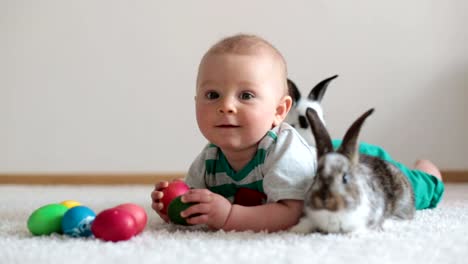 Little-toddler-child,-baby-boy,-playing-with-bunnies-and-easter-eggs-at-home,-colorful-hand-drawings-on-the-eggs.