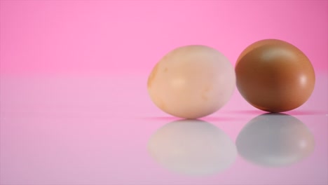 Two-eggs-are-spinning-on-a-table-on-a-pink-background