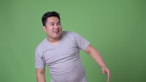 Young-handsome-overweight-Asian-man-against-green-background