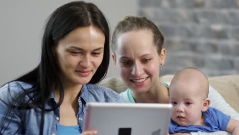 Weibliches-Paar-mit-Baby-Blick-auf-Tablet