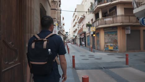 Male-city-dweller-is-walking-in-narrow-lane-with-small-crossroads-in-daytime