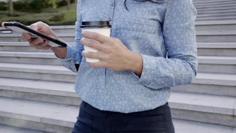 Tiro-medio-de-mujer-joven-atractiva-con-café-y-smartphone