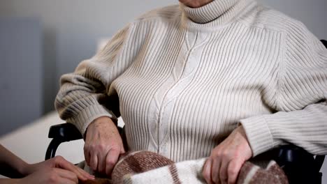 Woman-gently-covering-old-handicapped-female-with-plaid,-volunteer-support