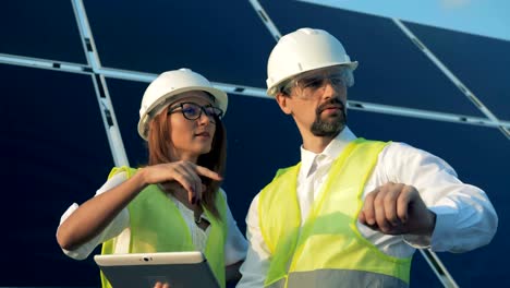 Solar-engineers-working-with-a-tablet-near-sun-batteries,-close-up.