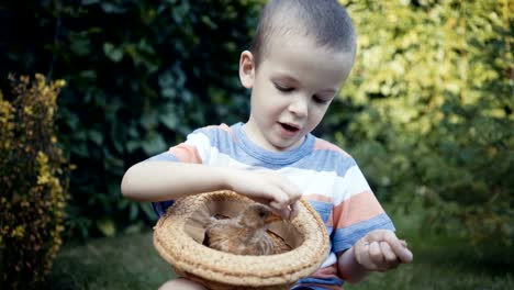 Filmmaterial-Bauernjunge-hält-eine-kleine-Küken-in-den-Händen-im-Freien.