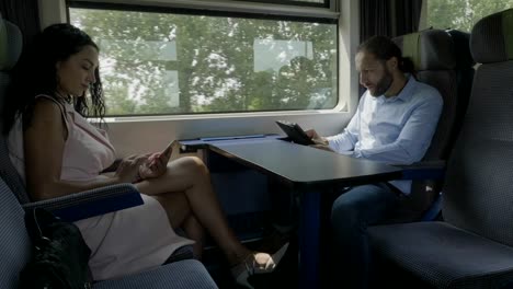 Mujer-y-hombre-viajando-en-tren-siendo-no-comunicativo-usando-sus-smartphones-para-pasar-tiempo-adicto-a-las-redes-sociales-en-línea