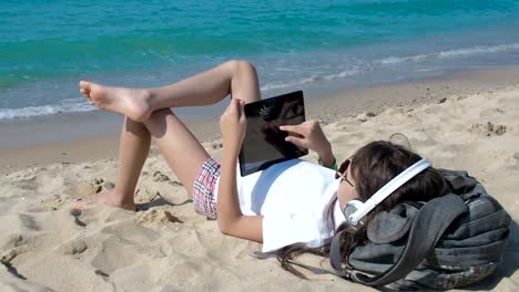 Niño-escuchando-música-en-la-playa.-Uso-de-la-tableta.