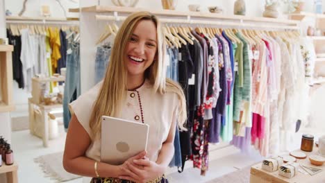 Female-owner-of-independent-clothing-store-with-digital-tablet-smiling-at-camera---shot-in-slow-motion