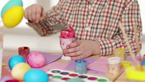 Niño-feliz-vistiendo-orejas-de-conejo-pintando-huevos-el-día-de-Pascua.