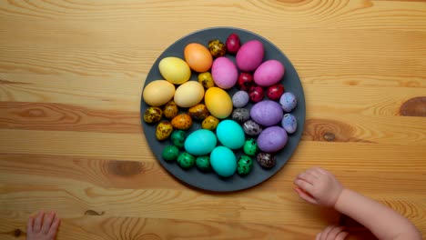 las-manos-de-los-niños-que-toman-huevos-de-Pascua-multicolor-de-un-plato