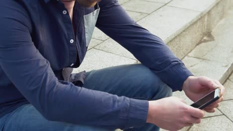 theme-is-man-and-social-networks.-young-Caucasian-sad-male-brunette-in-shirt-is-sitting-in-park-in-Letnec-waiting,-being-late-is-using-hand-to-hold-mobile-phone.-Emotion-resentment-and-disorder