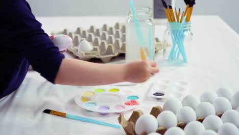 Niña-pequeña-pintando-huevos-de-Pascua-con-pintura-acrílica.