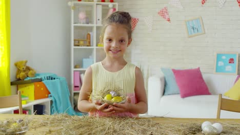 Feliz-niña-posando-con-huevos-de-Pascua-en-hay-Nest