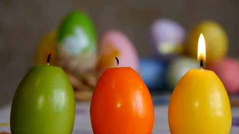 Velas-hechas-en-forma-de-huevo-de-Pascua.-Las-velas-se-extinguió-desde-el-aire..-Verde,-naranja,-amarillo.-Huevos-de-Pascua-velas-y-coloridos-huevos-de-Pascua-en-el-fondo.