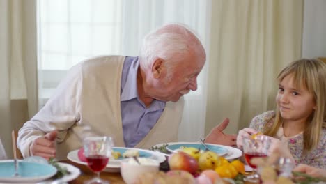 Großvater-spricht-mit-Enkelkindern-beim-Family-Dinner