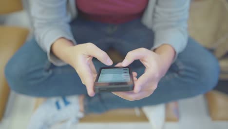 Asian-woman-using-smartphone-while-sitting-in-international-airport.