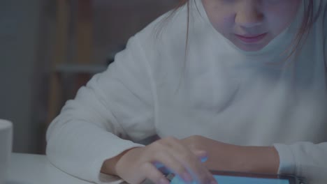 Young-asian-woman-working-late-using-tablet-checking-social-media-while-relax-on-desk-in-night-in-living-room-at-home.-Enjoying-time-at-home-concept.