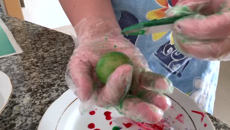 A-woman-in-gloves-paints-eggs