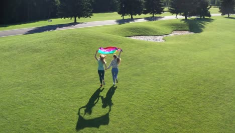 Drone-view-of-gay-couple-running-holding-lgbt-flag