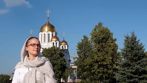 Orthodoxe-Lifestyle-Frau-im-Schal-steht-auf-dem-Hintergrund-der-orthodoxen-Kirche