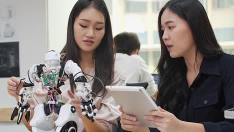 Asian-woman-engineer-assembling-and-testing-robotics-responses-in-laboratory.-Architects-design-circuit-meeting-share-technology-ideas-and-collaborating-development-robot.