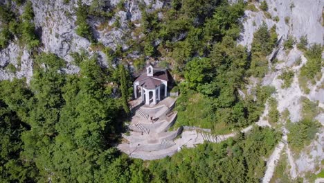 aerial-shot-of-amazing-house-inside-cliff-in-italian-mountains-in-sunny-summer-day,-view-from-birds-eye