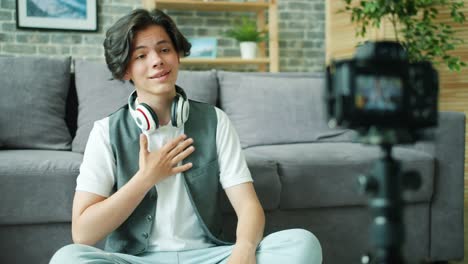 Cheerful-teenager-talking-gesturing-in-front-of-camera-recording-video-for-vlog