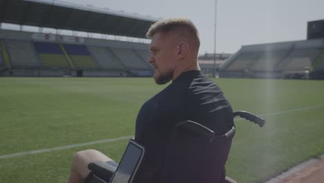 Disabled-athlete-sitting-in-wheelchair-by-a-sports-field