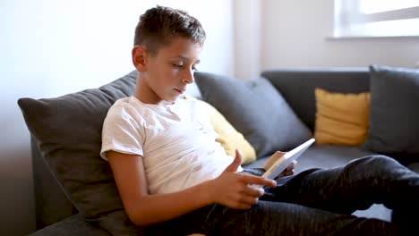 Young-boy-is-playing-games-on-his-tablet-at-home