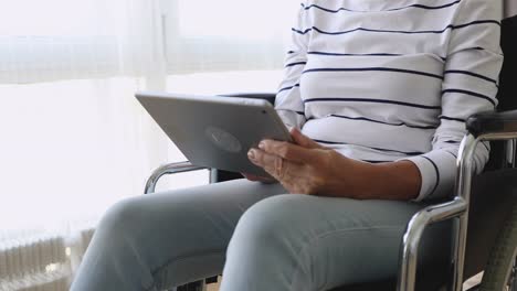 Behinderte-alte-Frau-sitzen-auf-Rollstuhl-mit-digitalen-Tablet,-Nahaufnahme