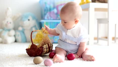 Süßes-Kleinkind-Kind,-Baby-Junge,-im-sonnigen-Wohnzimmer-spielen-mit-Ostern-Schokolade-Hase-und-bunte-Ostereier