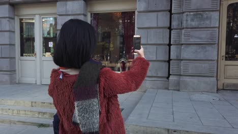 Mujer-asiática-tomando-fotos-por-la-cámara-del-teléfono-móvil-en-la-calle-Europa