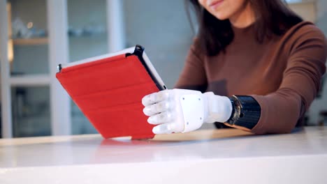 Woman-holds-a-tablet-with-robotic-hand,-close-up.