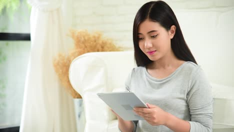 Asiatische-Frau-mit-Ipad-Shopping-Online-Website-auf-dem-Smartphone-mit-lächelndem-Gesicht.-Glück-asiatische-Frau-hält-Handy-Checking-Mail-von-Online-Shopping-Website-lesen-Artikel-Blog-vlog-Social-Media