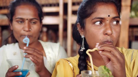 Dos-mujeres-que-beben-bebidas-usando-tecnología-en-café