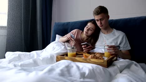 Süßes-Paar-Surfen-mit-Smartphones-im-Bett