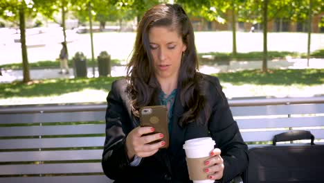 Beautiful-woman-reading-mobile-phone-app-technology-on-park-bench